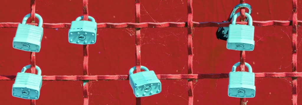 Padlocks on a fance in front of a red wall