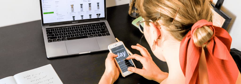 Photo of woman in orange shirt using iphone and laptop